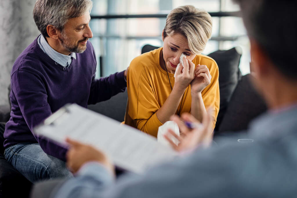 sad woman crying while being with her husband on a therapy with